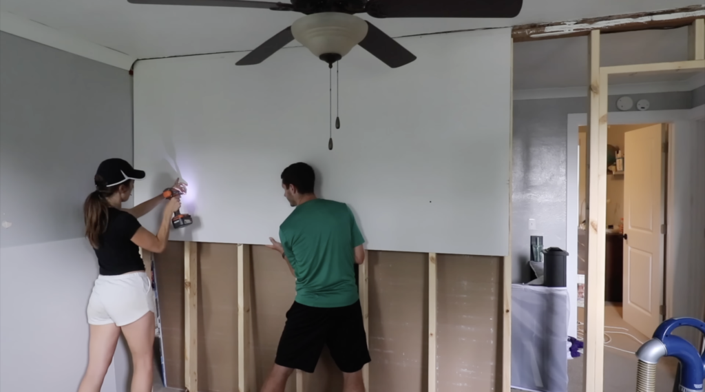 my husband helping me put the top sheet of drywall up 